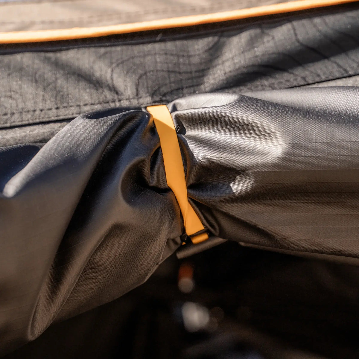 Close-up of a yellow clip securing two pieces of black fabric together—likely part of the CVT 180 Degree Awning—providing instant shade for your outdoor shelter.