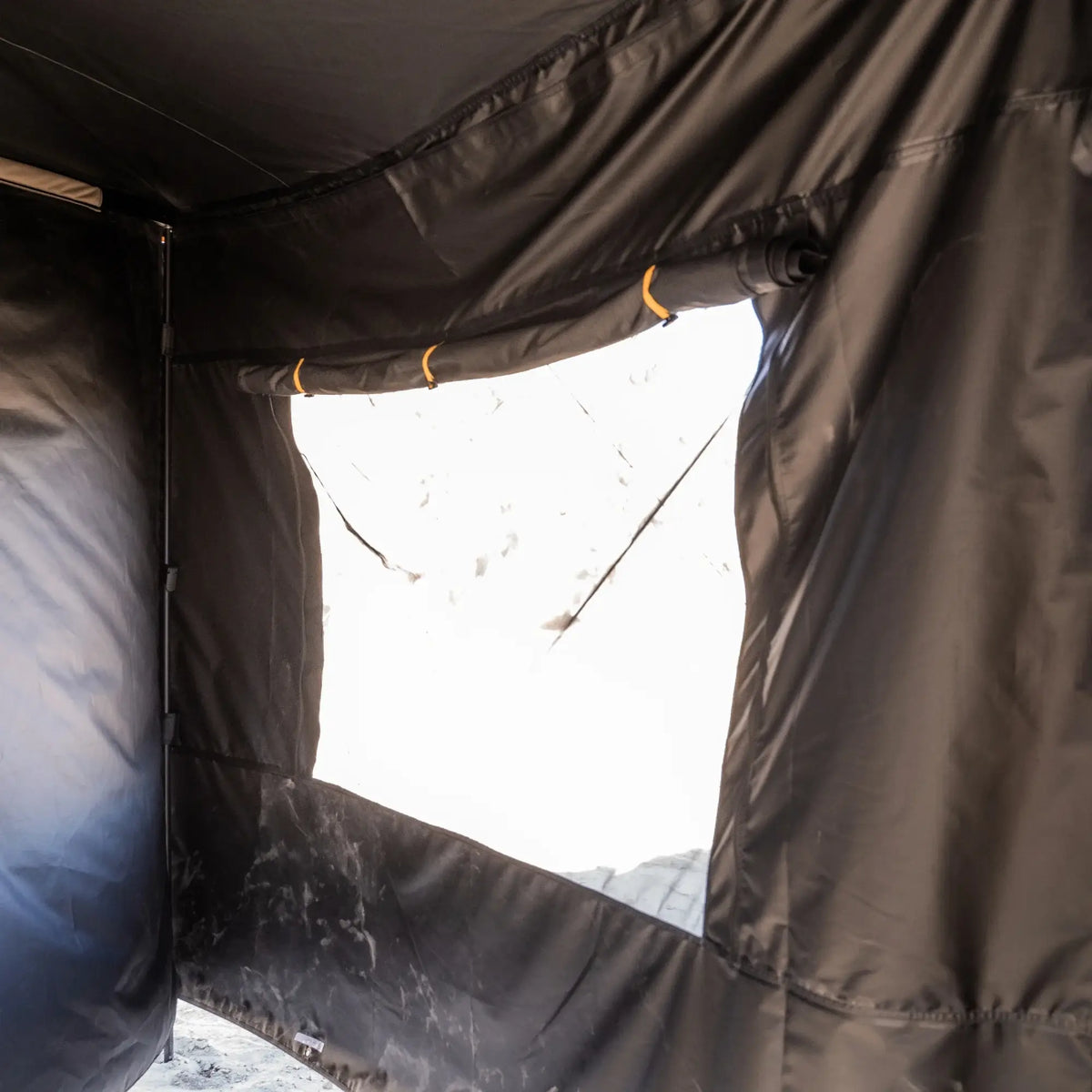 A close-up of the CVT 270 Degree Awning Wall in black fabric, featuring a large clear window rolled up and secured with elastic bands, allowing bright sunlight to enter while offering excellent weather protection.