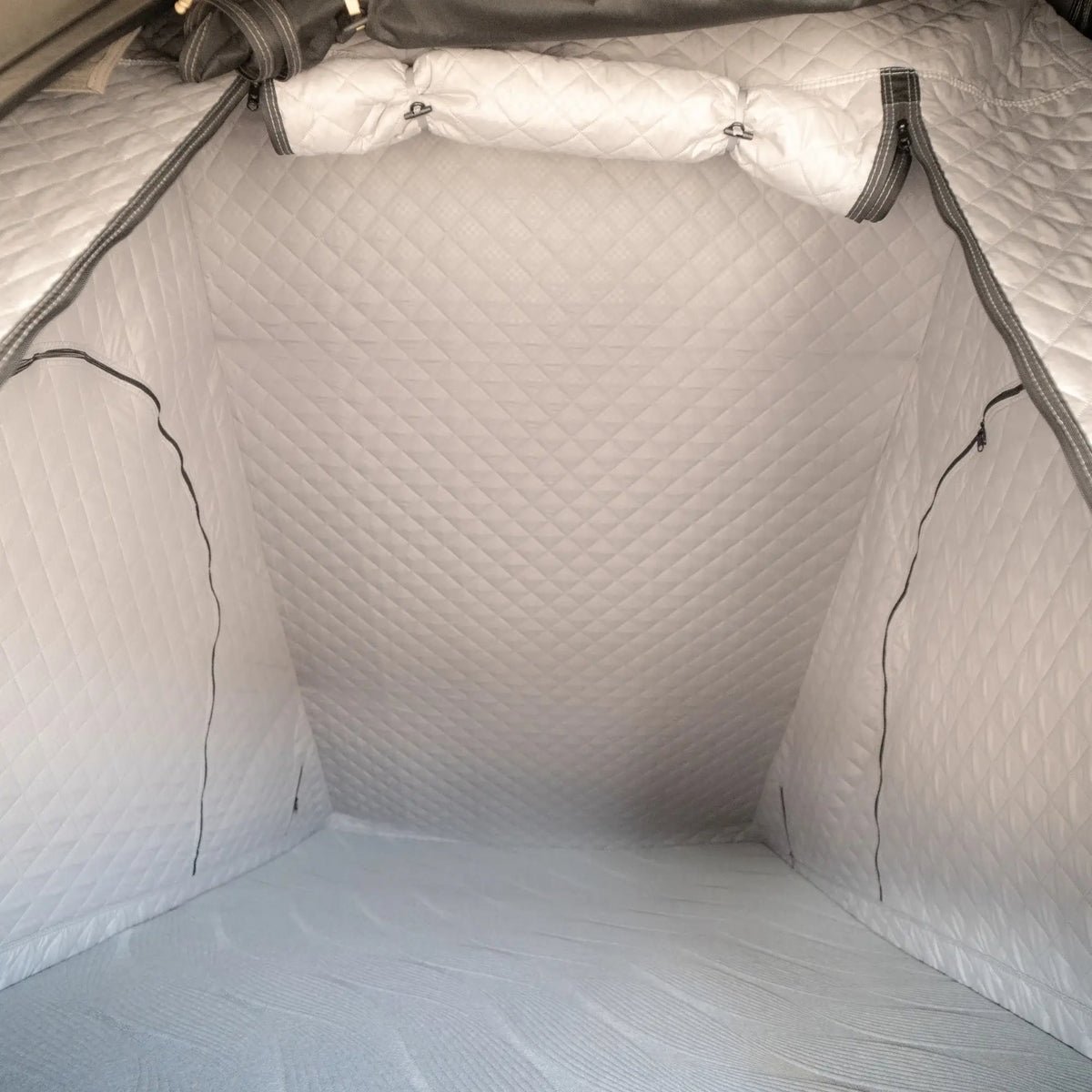 The photo displays the interior of a CVT Mt. Hood Insulation Walls shelter, featuring a gray, quilted design with zippered side panels and a diamond-patterned insulated liner engineered to maximize warmth during cold-weather camping.