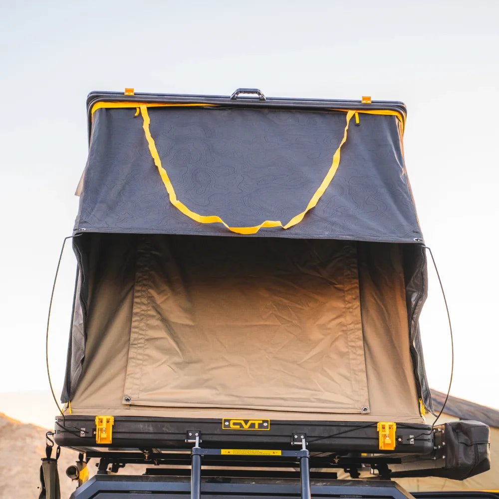 A CVT Mt. Hood Handle is installed below the entrance of a rooftop tent with yellow trim set up on top of a vehicle, offering a secure grip for safe access via the attached ladder, all set against a clear sky background.