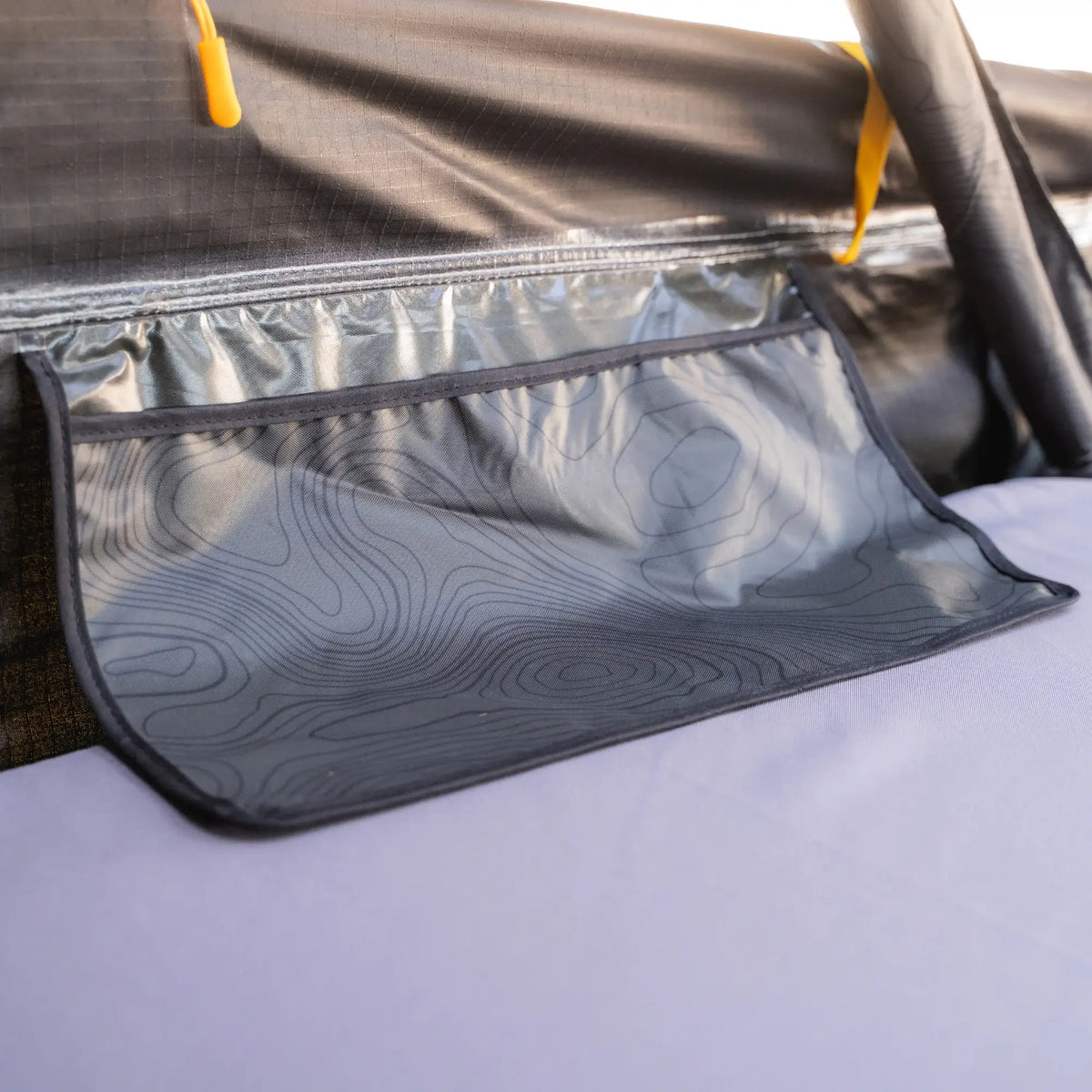 Close-up of a mesh storage pocket with a topographic pattern inside the CVT Pioneer 2 Softshell Tent, attached to the tent wall above a sleeping pad—perfect for keeping essentials organized during overland adventures.