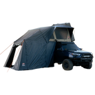 A dark-colored SUV featuring a CVT Wasatch Annex rooftop tent with an attached awning shelter, fully set up for camping on a light background. The Wasatch Annex by CVT extends from the tent over the side of the vehicle to the ground, providing rugged protection and creating a spacious camping shelter.