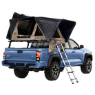 A blue pickup truck with a CVT Wasatch Hardshell Tent in black and tan mounted over the bed, accessible by a metal ladder. The tent is open, revealing its interior and ready for an overland adventure.