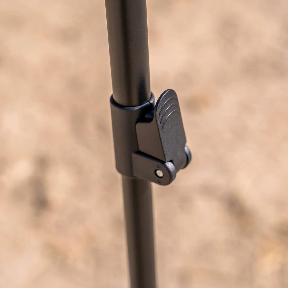 A close-up of a black adjustable pole with a locking lever mechanism—an essential support for the CVT 270 Degree Awning—set against a blurry outdoor background.