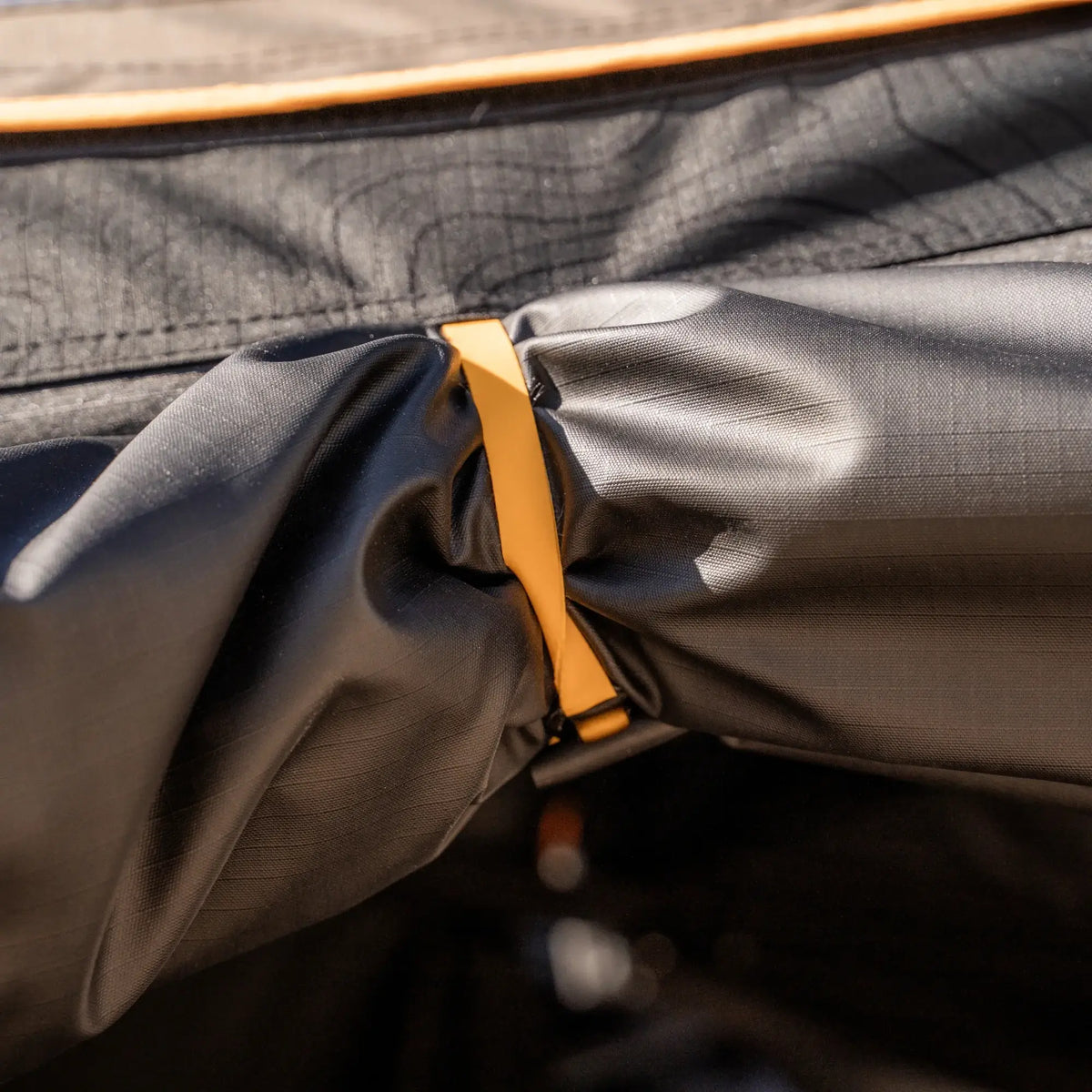 Close-up of a yellow strap securing black fabric on the CVT 270 Degree Awning Wall, featuring visible texture and reinforced stitching on weather-protective material.