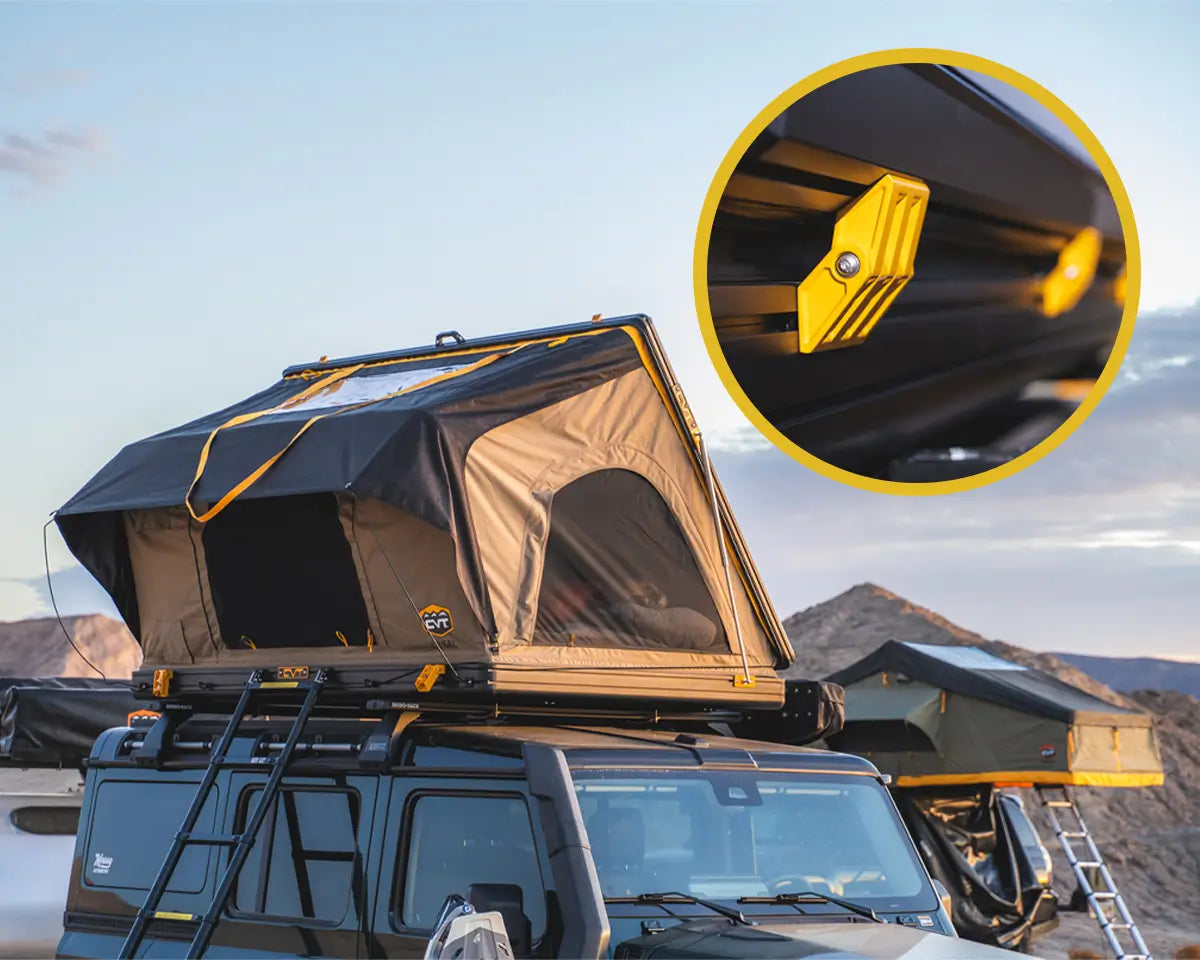 A rooftop tent is mounted on a vehicle in a desert setting. An inset shows a close-up of a yellow mounting bracket attached to the tent frame. Another car with a rooftop tent is visible in the background.