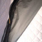 A close-up of a partially unzipped black zipper on gray fabric, bordered by quilted white panels, showcases the CVT Mt. Hood Insulation Walls—an insulated liner engineered to boost tent warmth during cold-weather camping.