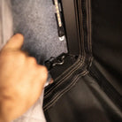 A hand pulls back a corner of the gray fabric, revealing a latch attached to a black surface with visible stitching—features of the CVT Mt. Hood Insulation Walls, designed for tent warmth—with an LED strip visible above.