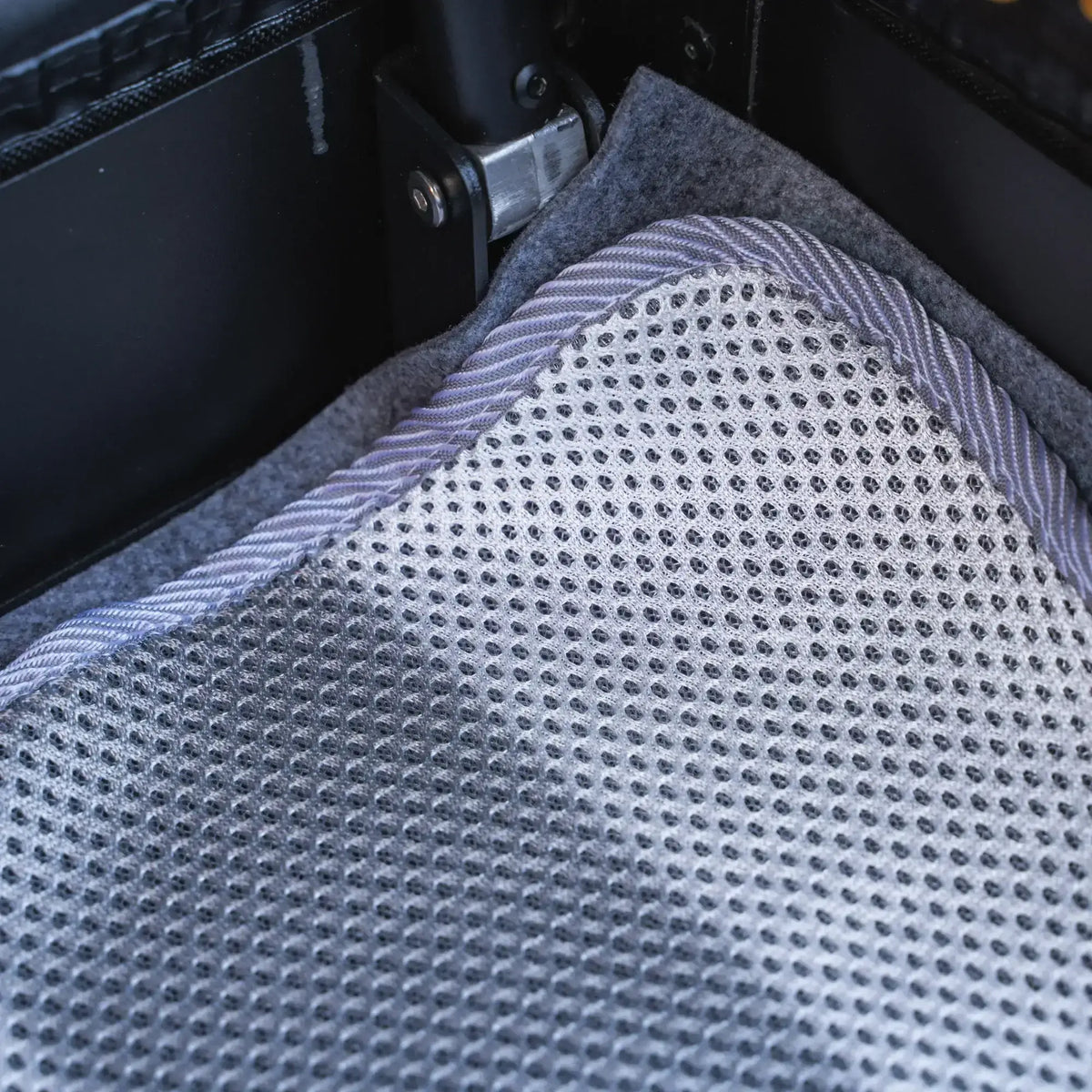 Close-up of the CVT Anti Condensation Mat in grey and white, featuring a textured mesh pattern. The mat is placed inside a black crate or container, highlighting part of a metal hinge and suede-like lining for effective moisture protection.