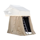 A rooftop tent with tan fabric by CVT is mounted on a vehicle, featuring a black ladder leading to the entrance and a CVT Pioneer Annex below for added enclosed space and privacy.