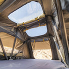 Interior view of the CVT Pioneer 2 Softshell Tent, featuring a spacious mesh roof and large window panels that reveal a blue sky and rugged rocky landscape outside. Ideal for overland adventures, with yellow straps and gray fabric visible inside the tent.