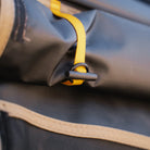 A close-up of the CVT Mt. Hood/La Sal Shoe Bag shows a yellow strap with a black toggle securing rolled-up dark fabric, accented by beige trim at the edge—highlighting its practical outdoor gear design.