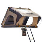 Introducing the CVT La Sal Hardshell Tent—a beige and black rooftop tent featuring a spacious comfort interior, side-open design with an open entrance and mesh windows for ventilation. Mounted on a sturdy platform, it includes a convenient ladder for access and a hanging storage bag below the entrance for added organization.