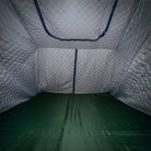 Interior view of an empty CVT tent featuring Pioneer Insulation Walls with quilted silver fabric and diamond-patterned stitching, a green floor, and zippered openings—designed for cold weather camping.