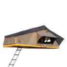 The CVT Pioneer 2 Softshell Tent is mounted on a vehicle and features a ladder leading up to its open entrance. This tan tent, accented with yellow and black, has a partially open window flap—making it an ideal setup for overland adventures.