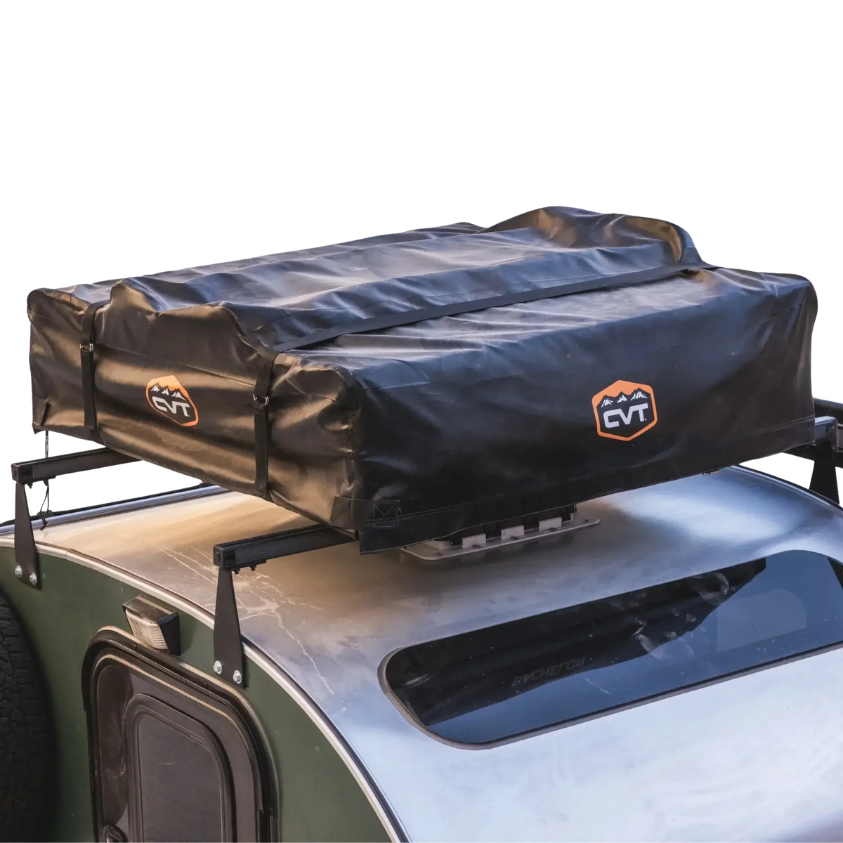 A black CVT rooftop tent is securely mounted on top of a green vehicle with a roof rack. The tent is folded and protected by the Pioneer Travel Cover from CVT, which features weather-resistant material and displays the CVT logo with orange and white accents.