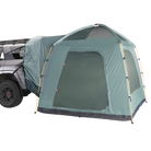 A CVT Timber Creek SUV Tent in green, featuring a dome-style design, is secured to the rear of a gray vehicle—providing an extended, sheltered camping area that offers comfort and convenience for overlanders on their adventures.